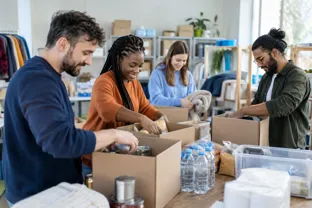 Charity volunteers packing donated food and supplies in a community centre
