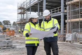 Construction professionals reviewing architectural plans on a UK building site