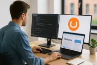 Image of a man looking at a laptop with two monitors