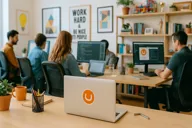 Image of an open laptop with an Umbraco sticker and people working at their desks in the background